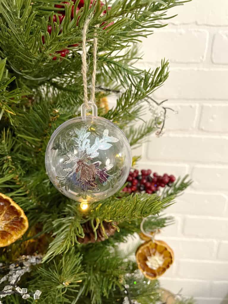 A glass ball ornament hangs on a christmas tree.