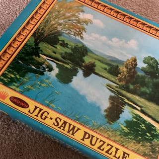 A box of jig saw puzzles with a picture of a lake.