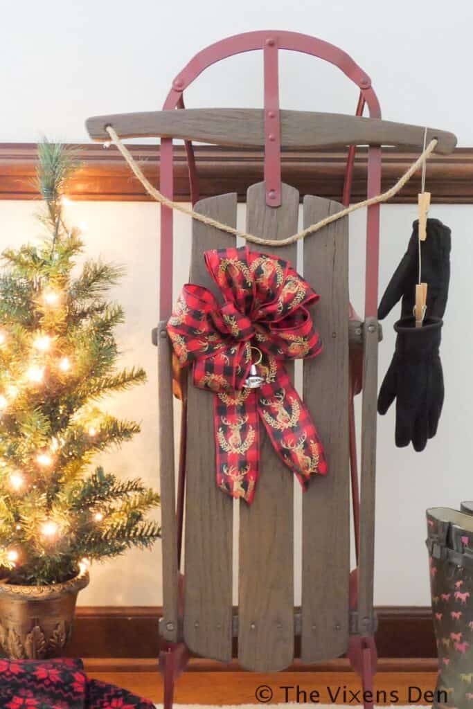 A wooden sled with a bow on it and a christmas tree.