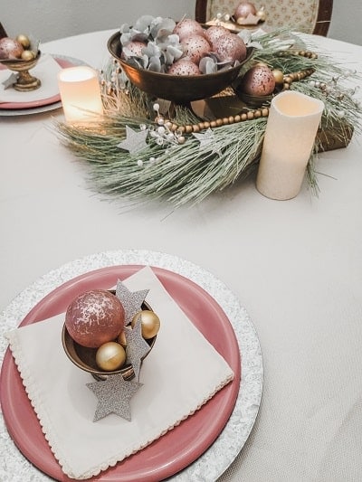 A christmas table setting with gold and pink ornaments.