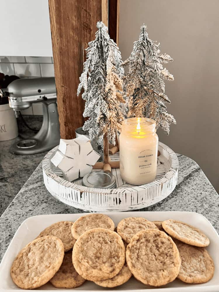 A plate of cookies and a candle on a counter.
