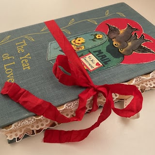 A book with a red ribbon and a bird on it.