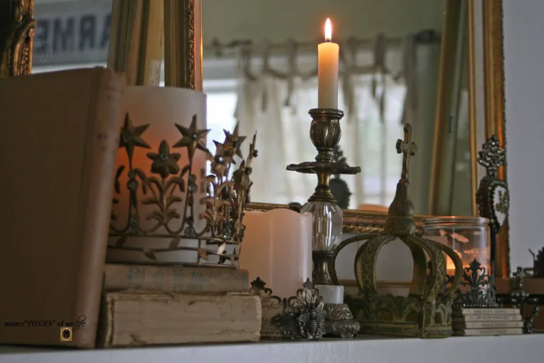 A mantle with candles, books and a mirror.
