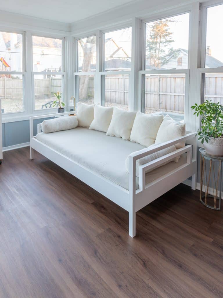 A white daybed in a room with hardwood floors.