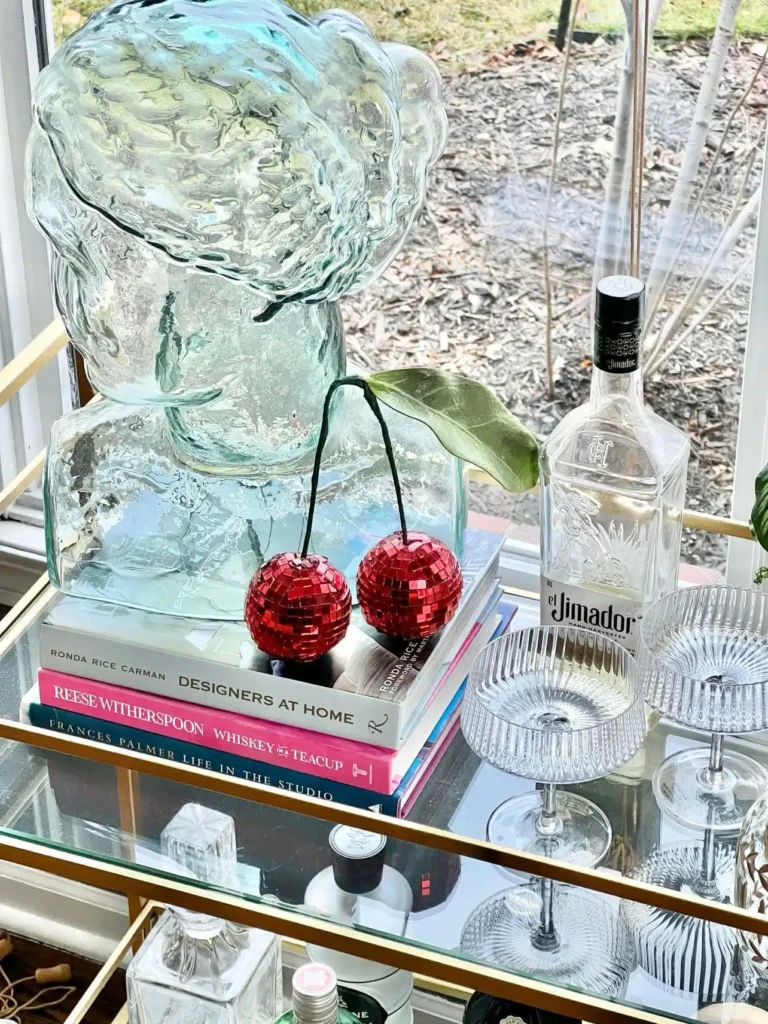 A glass bar cart with a bottle of wine and a bottle of liquor.