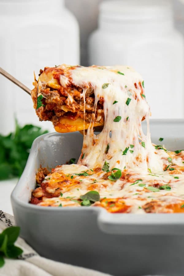 Lasagna being taken out of a casserole dish.