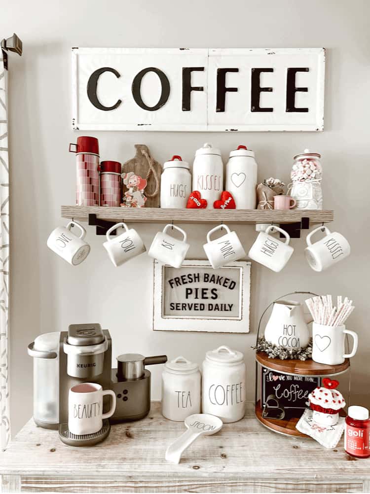 A white shelf with coffee mugs and a sign.