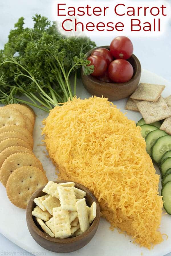 An easter-themed cheese ball shaped like a carrot, served with crackers and vegetables.