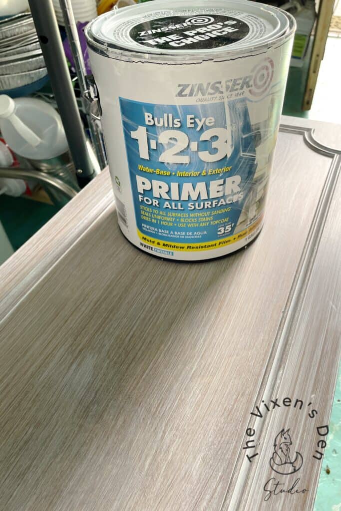 A can of zinsser bulls eye 1-2-3 primer on a wood surface in a workshop setting.