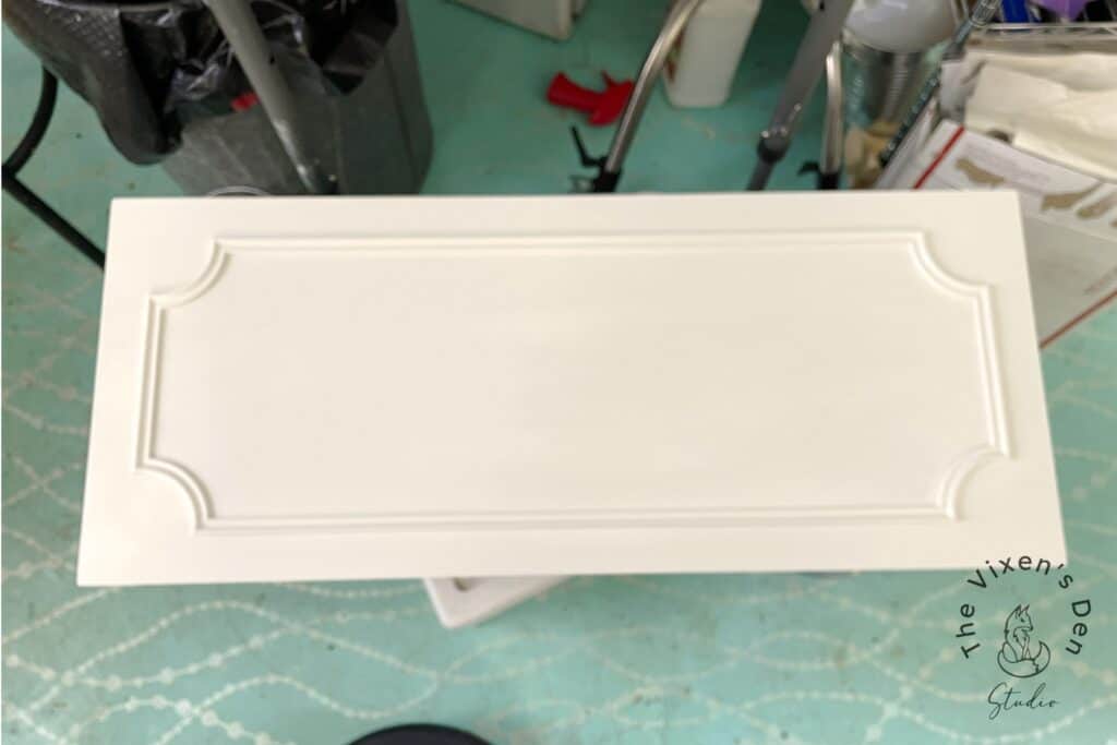 A white cabinet door with decorative trim on a work surface.