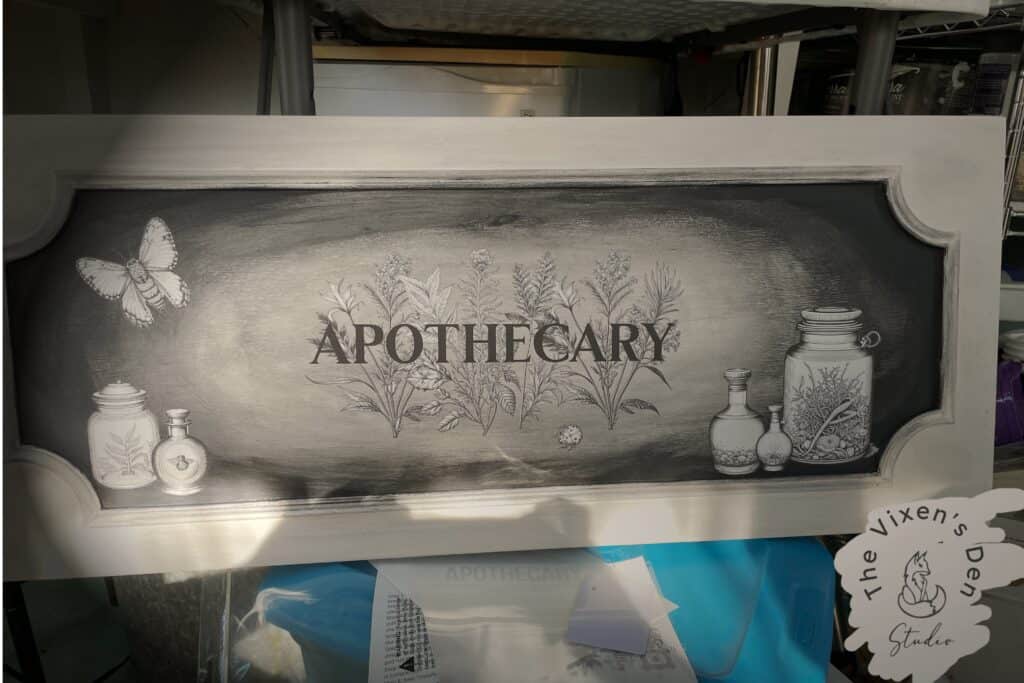 Vintage-style apothecary sign with floral and butterfly motifs displayed on a shelf.