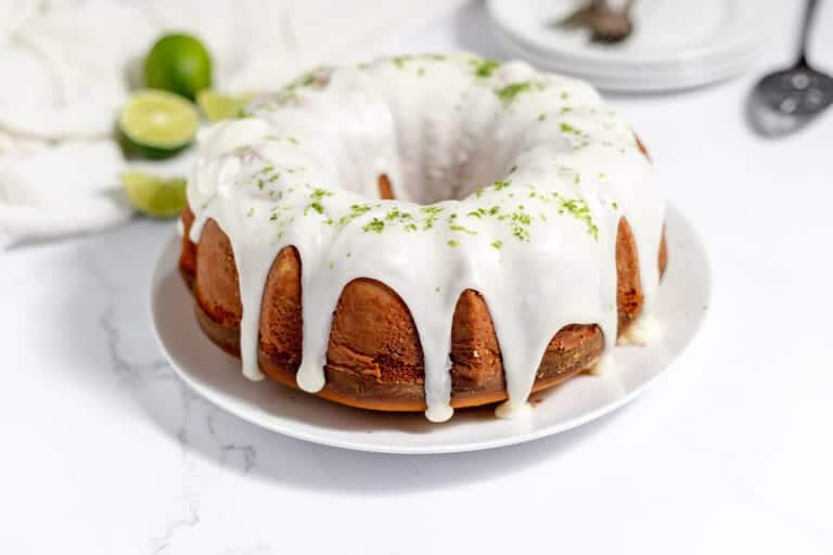 A bundt cake with lime icing on a white plate.