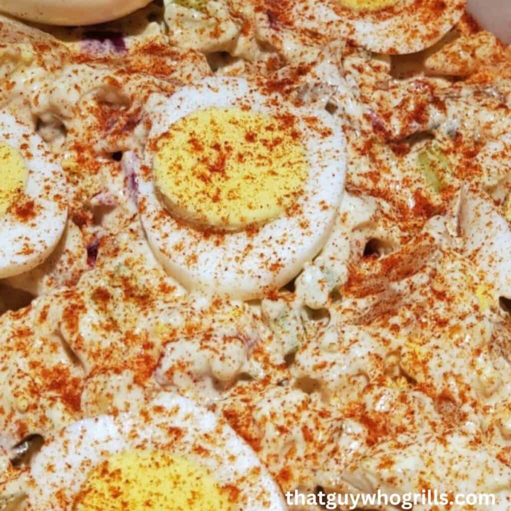A bowl of potato salad with hard boiled eggs and spices.