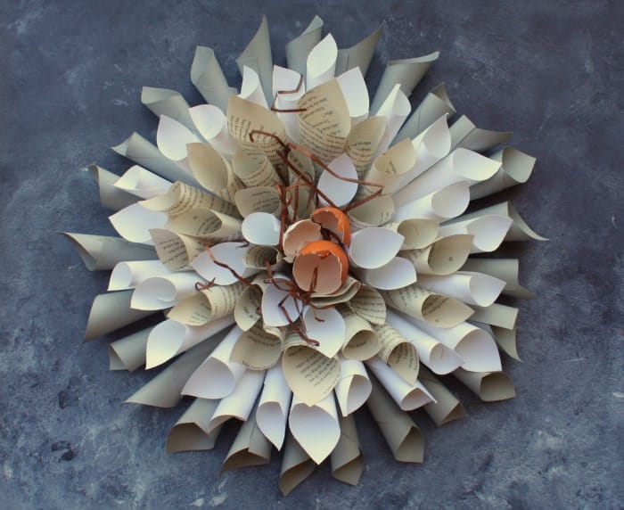 Decorative flower-shaped arrangement made from rolled book pages on a gray background.
