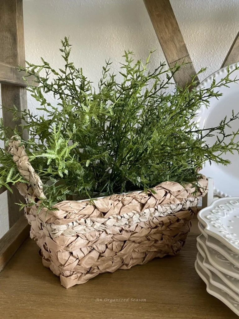 A wicker basket filled with a plant on a shelf.