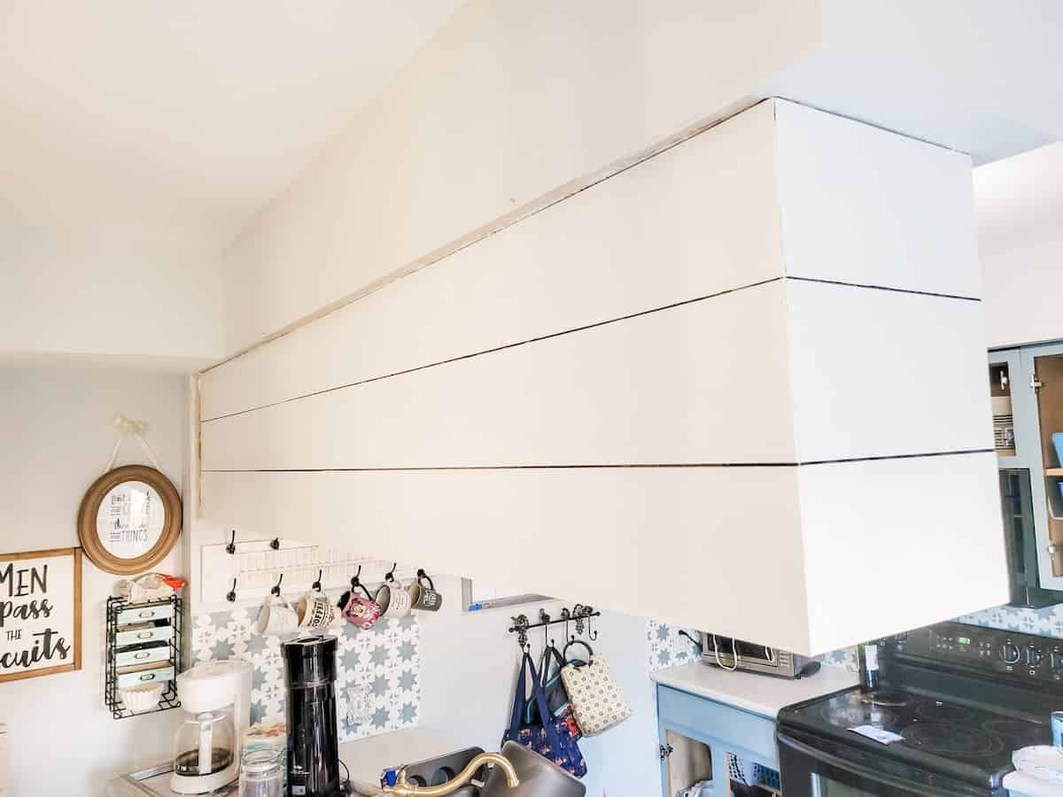 A corner of a kitchen with white cupboards, a tiled backsplash, and various kitchenware and decorative items.