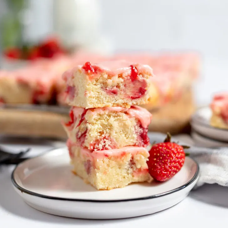 A piece of strawberry swirl cake on a plate with more slices in the background.