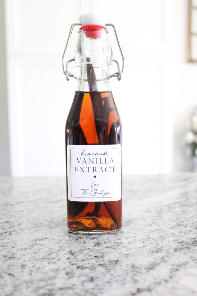 A bottle of homemade vanilla extract with a label, on a kitchen countertop.