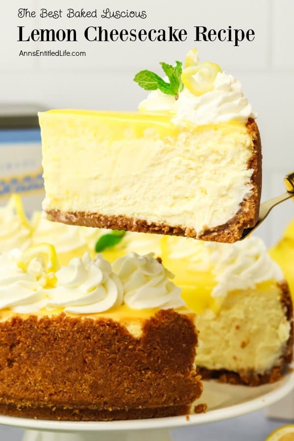 A slice of lemon cheesecake with a graham cracker crust is being lifted from a whole cheesecake. The cheesecake is topped with whipped cream and mint.