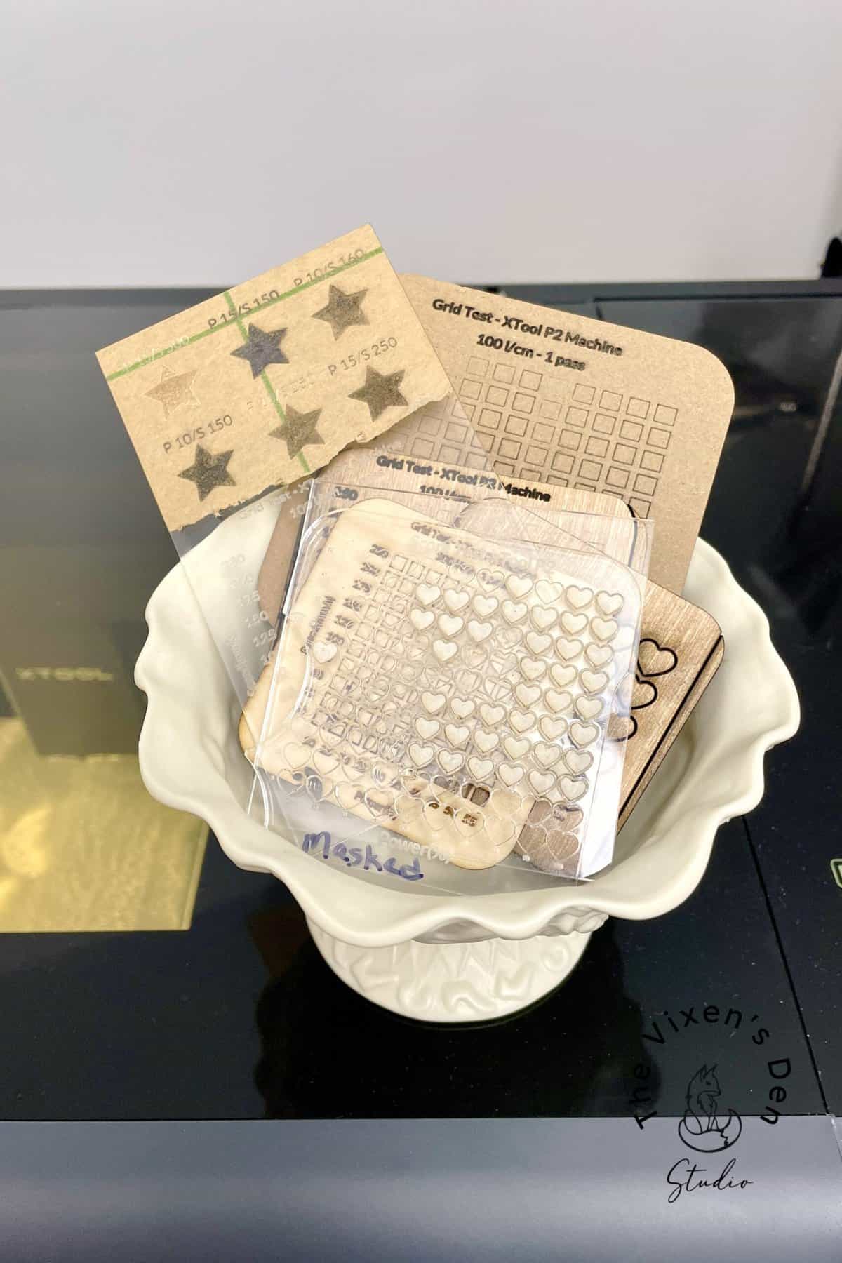 Various perforated cards with different patterns, including hearts and dots, arranged in a white bowl on a black surface.