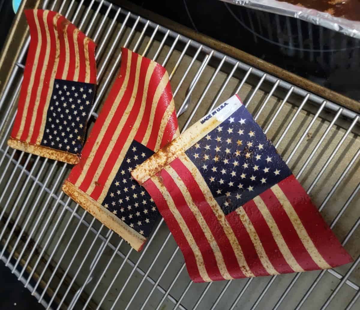 Three pieces of cooked bacon with American flag designs on a cooling rack.