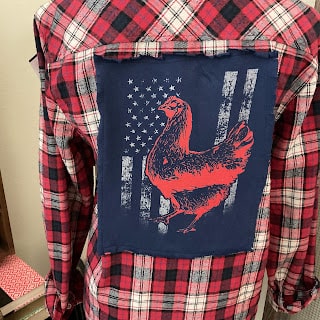 Red and black checkered shirt featuring a blue patch on the back with a red chicken and distressed U.S. flag design.