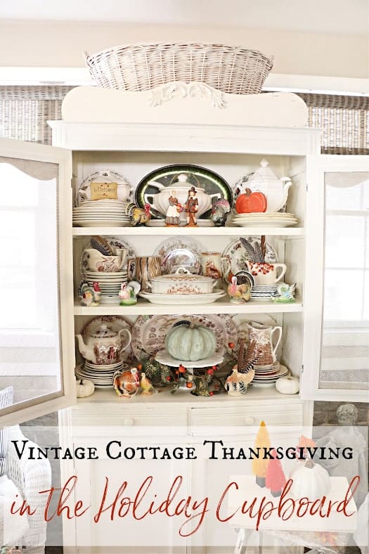 A vintage cupboard displays Thanksgiving-themed dishes and decor, including plates, cups, and pumpkins.