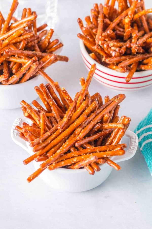 Bowls filled with pretzel sticks on a white surface.