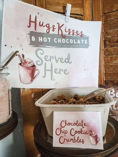 Sign with "Hugs & Kisses & Hot Chocolate Served Here" above a bowl labeled "Chocolate Chip Cookie Crumbles.