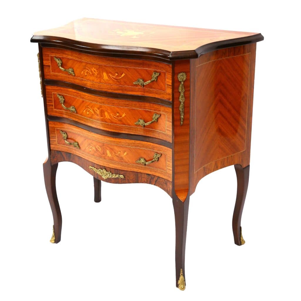 A vintage wooden chest of drawers with three ornate brass handles, curved legs, and decorative inlay on the surface.