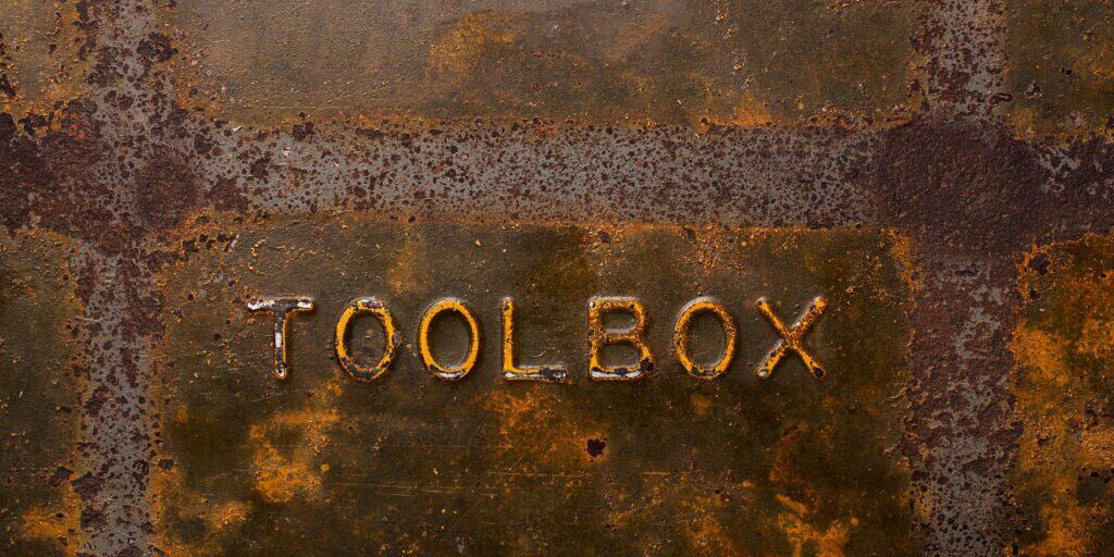 Close-up of a rusty metal surface with the word "TOOLBOX" embossed in capital letters.