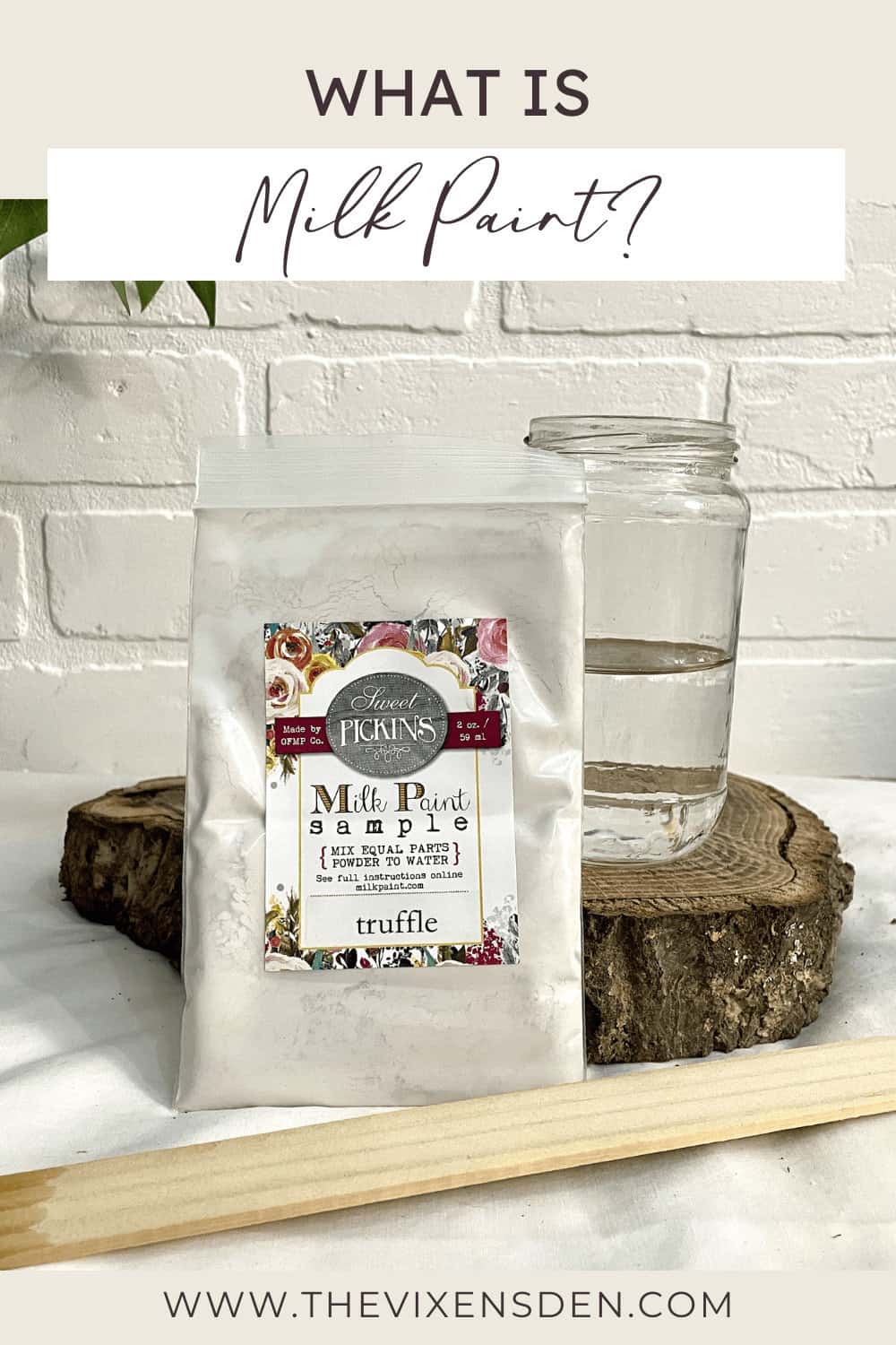 Bag of Sweet Pickins Milk Paint sample in "truffle" flavor, a jar of water, and a wooden stick displayed on a white surface with a brick wall background.