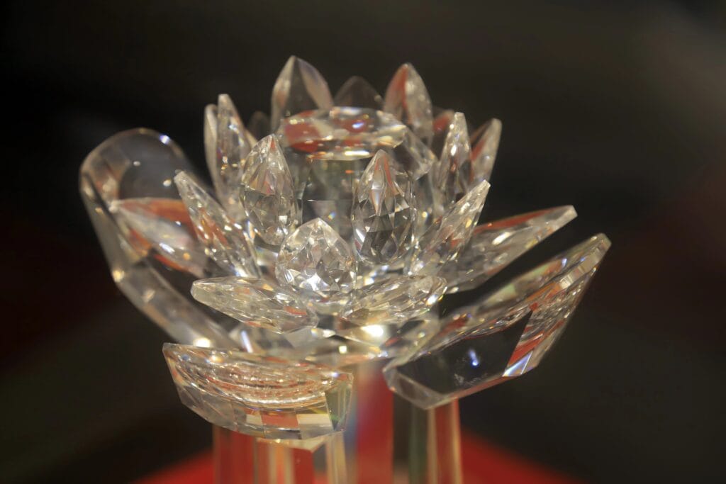 A clear crystal sculpture shaped like a blooming lotus flower, displayed against a dark background.