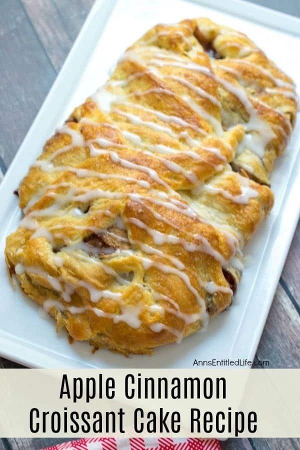 A baked apple cinnamon croissant cake drizzled with white icing, displayed on a rectangular white platter.
