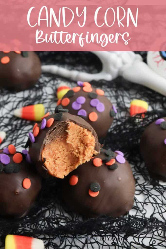 Chocolate-covered candy corn Butterfinger balls with orange filling, decorated with colorful sprinkles, are displayed on black netting with candy corn pieces scattered around.